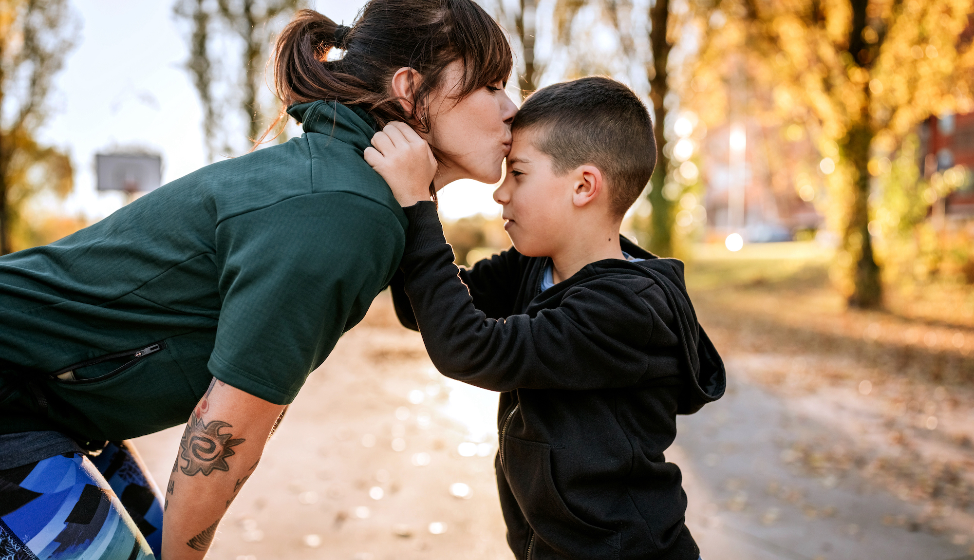Mom kisses son on forehead in the park